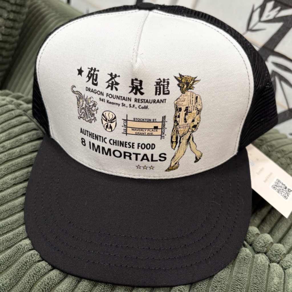 Black and white cap with Chinese characters and graphics on a green surface